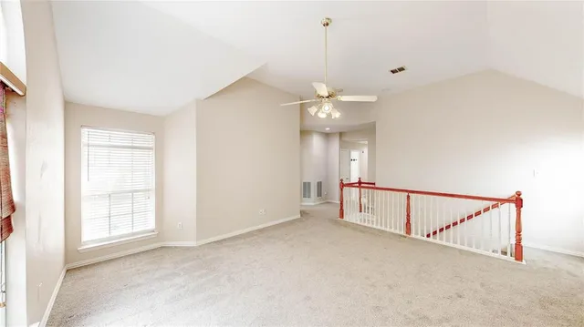 an empty room with chandelier fan and windows