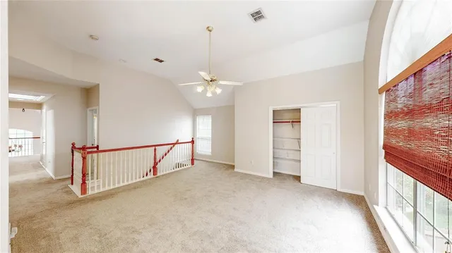 an empty room with chandelier fan and windows