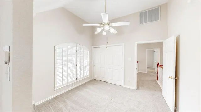 an empty room with windows and fan