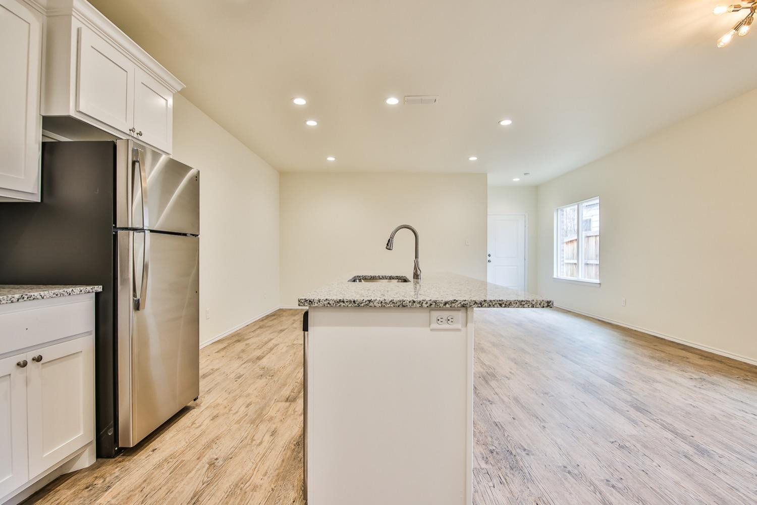 2004 23rd Street Lubbock, TX 79411 - Photo 11 of 26 a kitchen with stainless steel appliances granite countertop a refrigerator a sink dishwasher and a stove with wooden floor