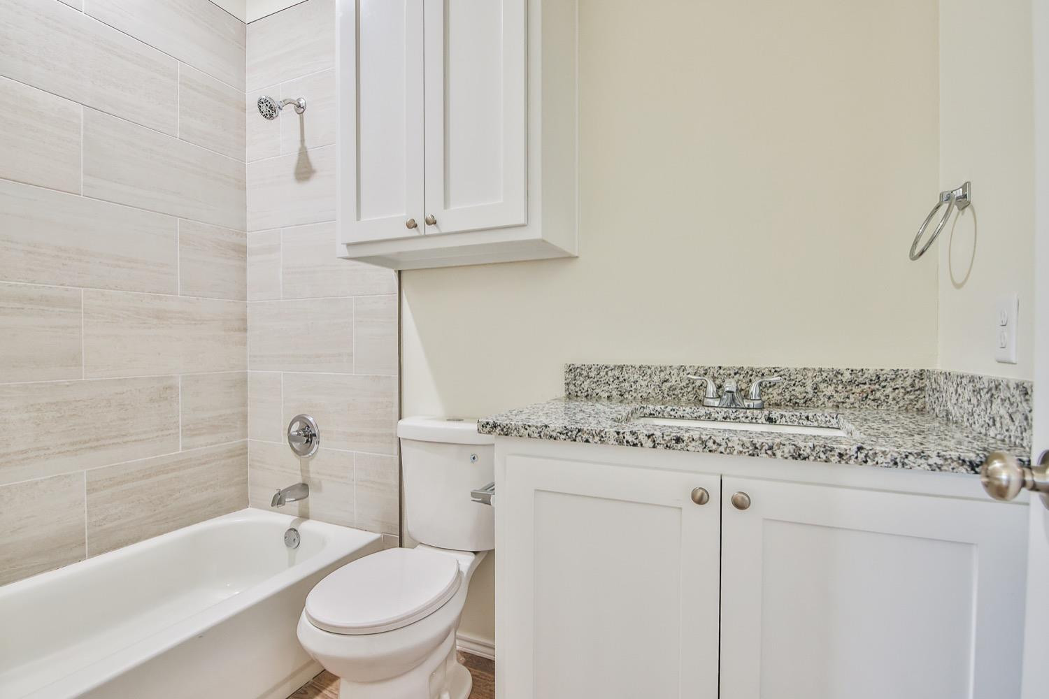 2004 23rd Street Lubbock, TX 79411 - Photo 16 of 26 a bathroom with a granite countertop toilet a sink and bathtub