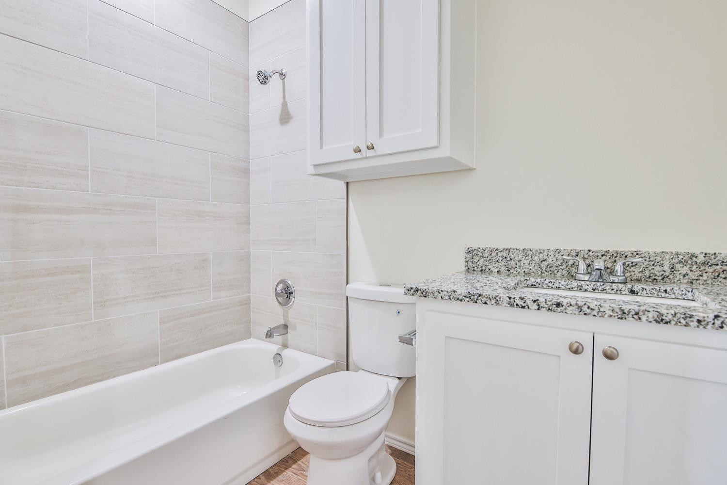 2004 23rd Street Lubbock, TX 79411 - Photo 17 of 26 a bathroom with a granite countertop toilet a sink and bathtub