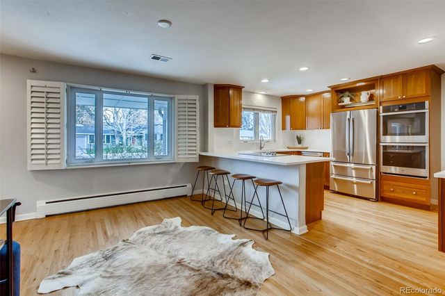 a living room with stainless steel appliances granite countertop furniture and a wooden floor