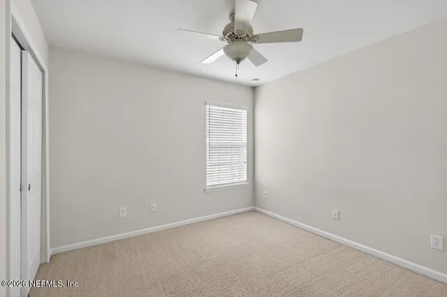 an empty room with a window and a ceiling fan