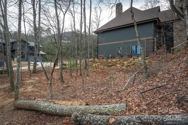 a backyard of a house with large trees and wooden fence