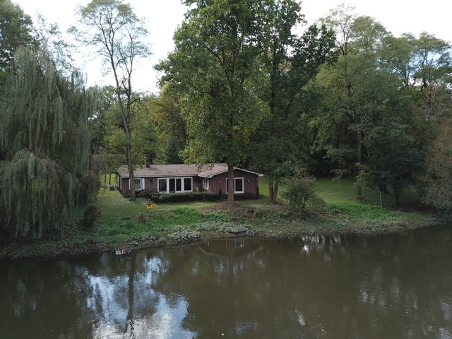 a view of a house next to a lake with a large tree