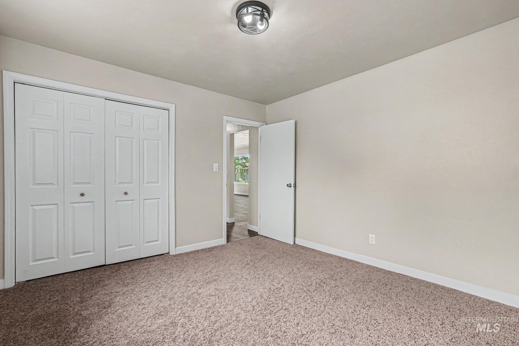 1023 State Street Weiser, ID 83672 - Photo 10 of 25 Carpeted room featuring a white bi-fold closet, a white interior door, a flush-mount ceiling light fixture, and light-colored walls
