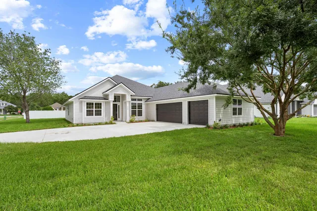 a view of a yard in front of a house with large trees