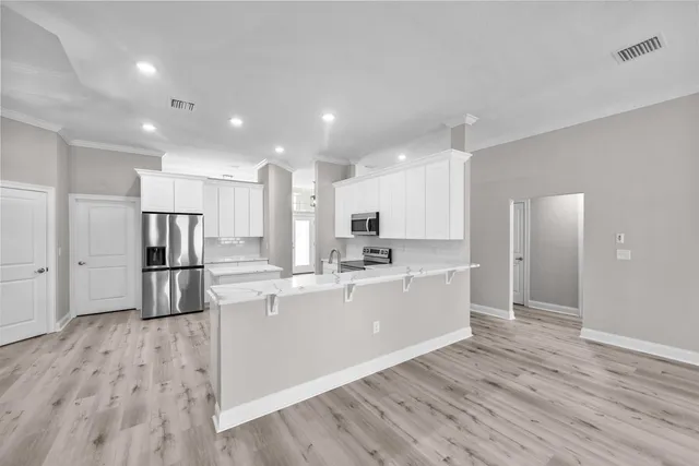 a kitchen with stainless steel appliances a refrigerator sink and white cabinets