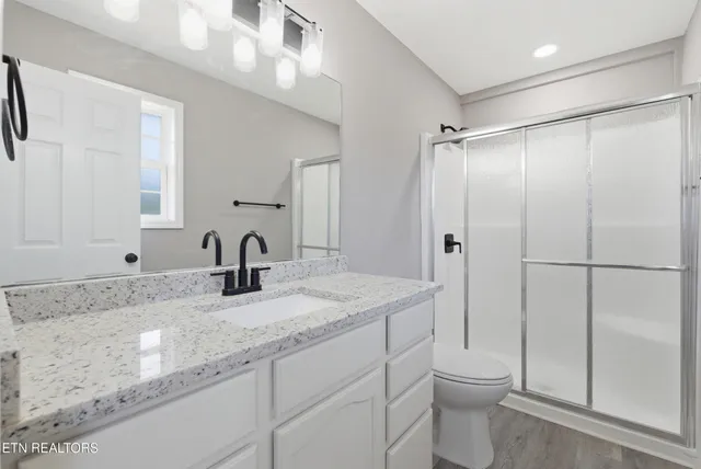 an empty room with wooden floor and ceiling fan