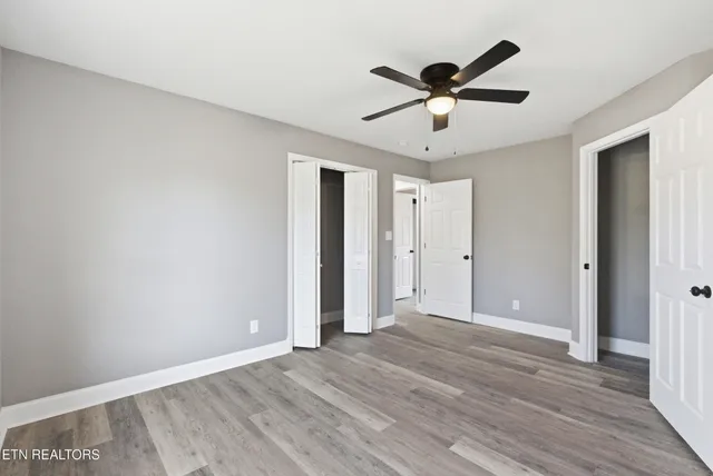 a view of an empty room with wooden floor fireplace and a window