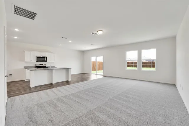 a view of kitchen with stainless steel appliances granite countertop a stove top oven a sink and a refrigerator