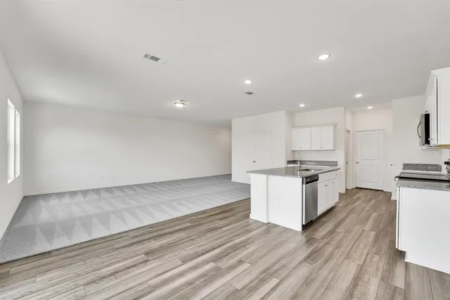 a kitchen with stainless steel appliances kitchen island granite countertop a stove a sink and a refrigerator