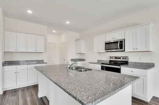 a kitchen with granite countertop a sink stove and microwave