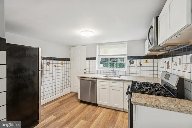 a kitchen with stainless steel appliances a sink a stove a refrigerator and wooden cabinets