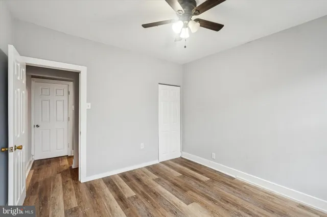 an empty room with a hardwood and ceiling fan