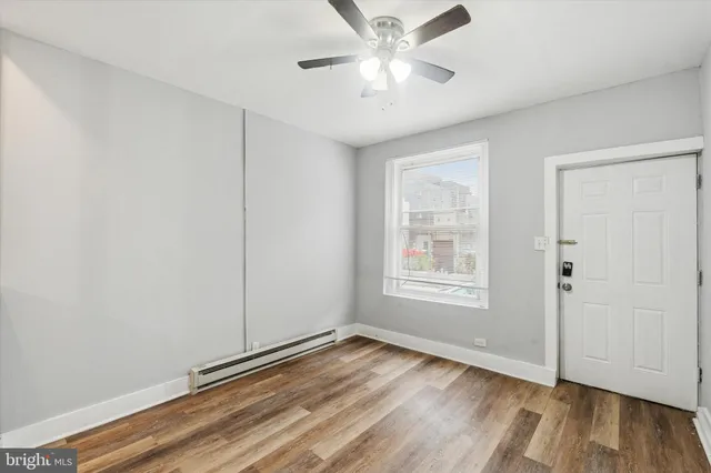 a view of an empty room with wooden floor and a window