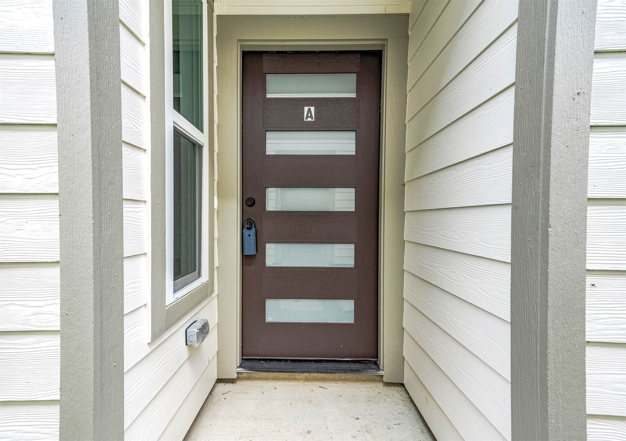 787 Fortune Street, Unit A Houston, TX 77088 - Photo 30 of 32 This photo features a modern front door with a sleek design, incorporating horizontal glass panels. It's set within a clean, neutral-toned entryway that highlights the contemporary style for the home.
