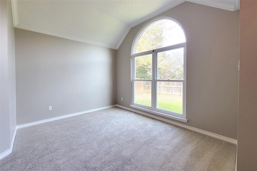 1604 Knoll Ridge Circle Corinth, TX 76210 - Photo 27 of 37 Vaulted ceilings with crown molding, arched top window, neutral wall tones, light gray carpeting, and white baseboards