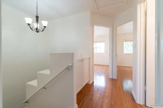 an empty room with wooden floor chandelier fan and window