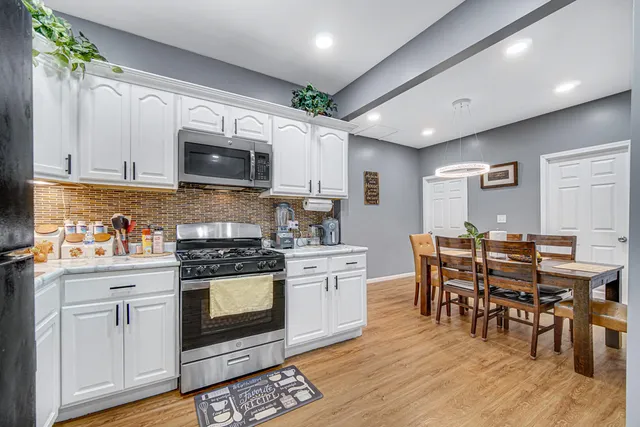 a kitchen with stainless steel appliances a stove a sink a microwave a dining table and chairs