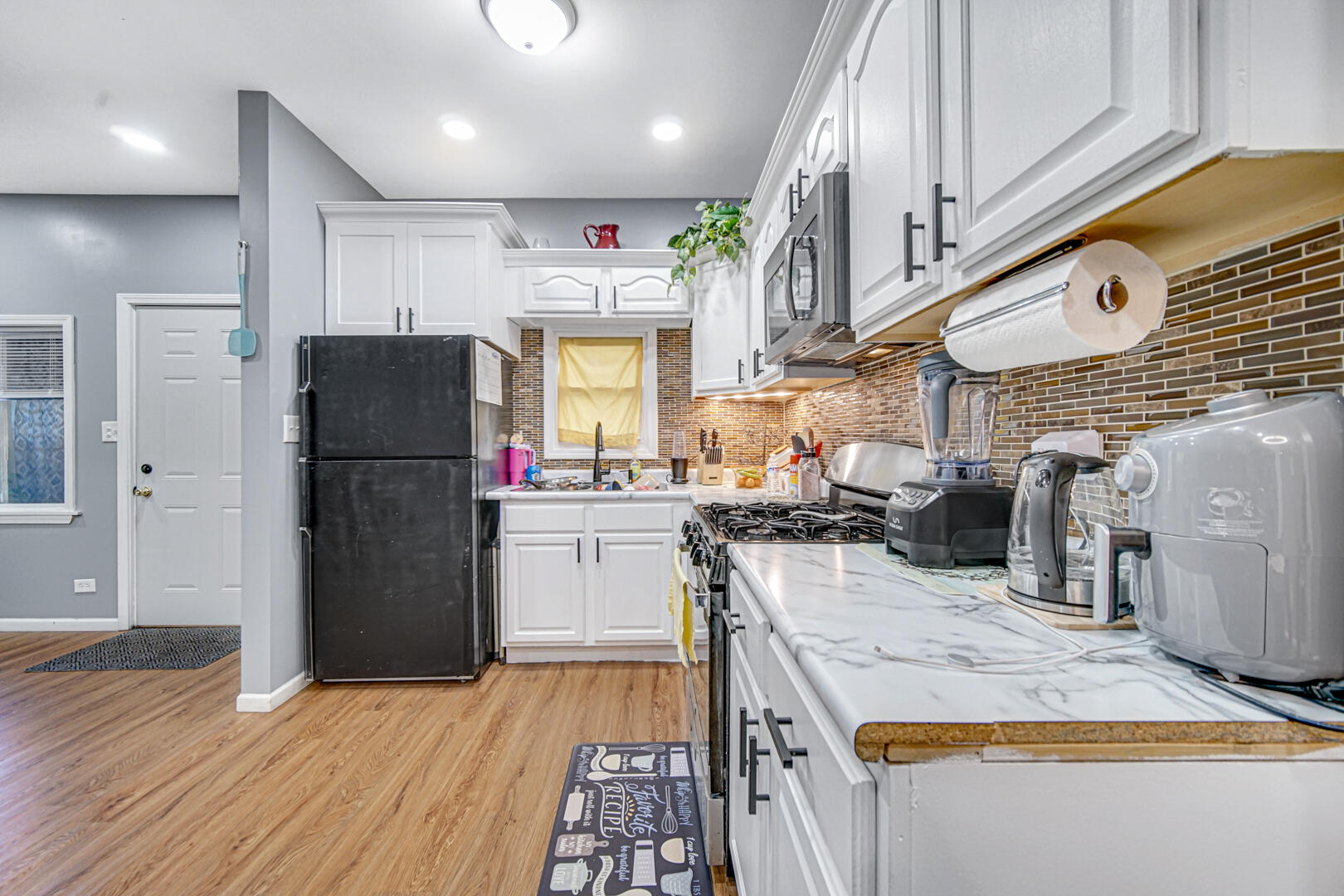1047 Ralston Street Gary, IN 46406 - Photo 6 of 16 a kitchen with a refrigerator a stove and a wooden floor