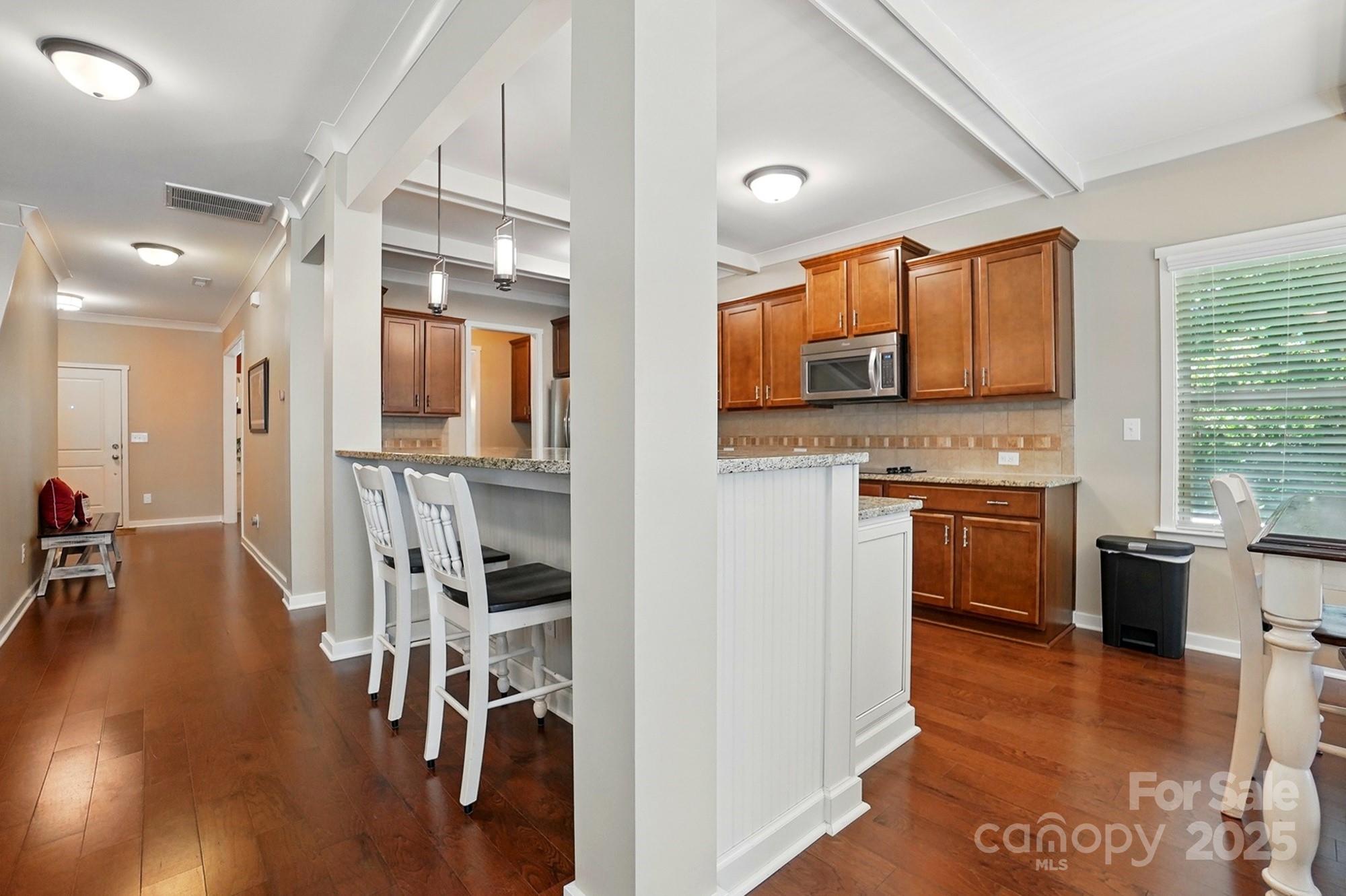 3106 Crosswind Drive Fort Mill, SC 29707 - Photo 18 of 43 a kitchen with stainless steel appliances a stove a sink dishwasher a refrigerator and a dining table with wooden floor