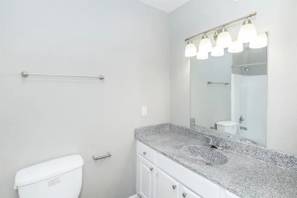 a bathroom with a granite countertop sink mirror and toilet