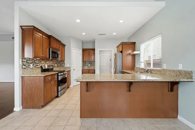 a kitchen with stainless steel appliances granite countertop a sink and a refrigerator