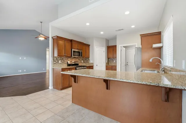 a large kitchen with granite countertop a sink and cabinets