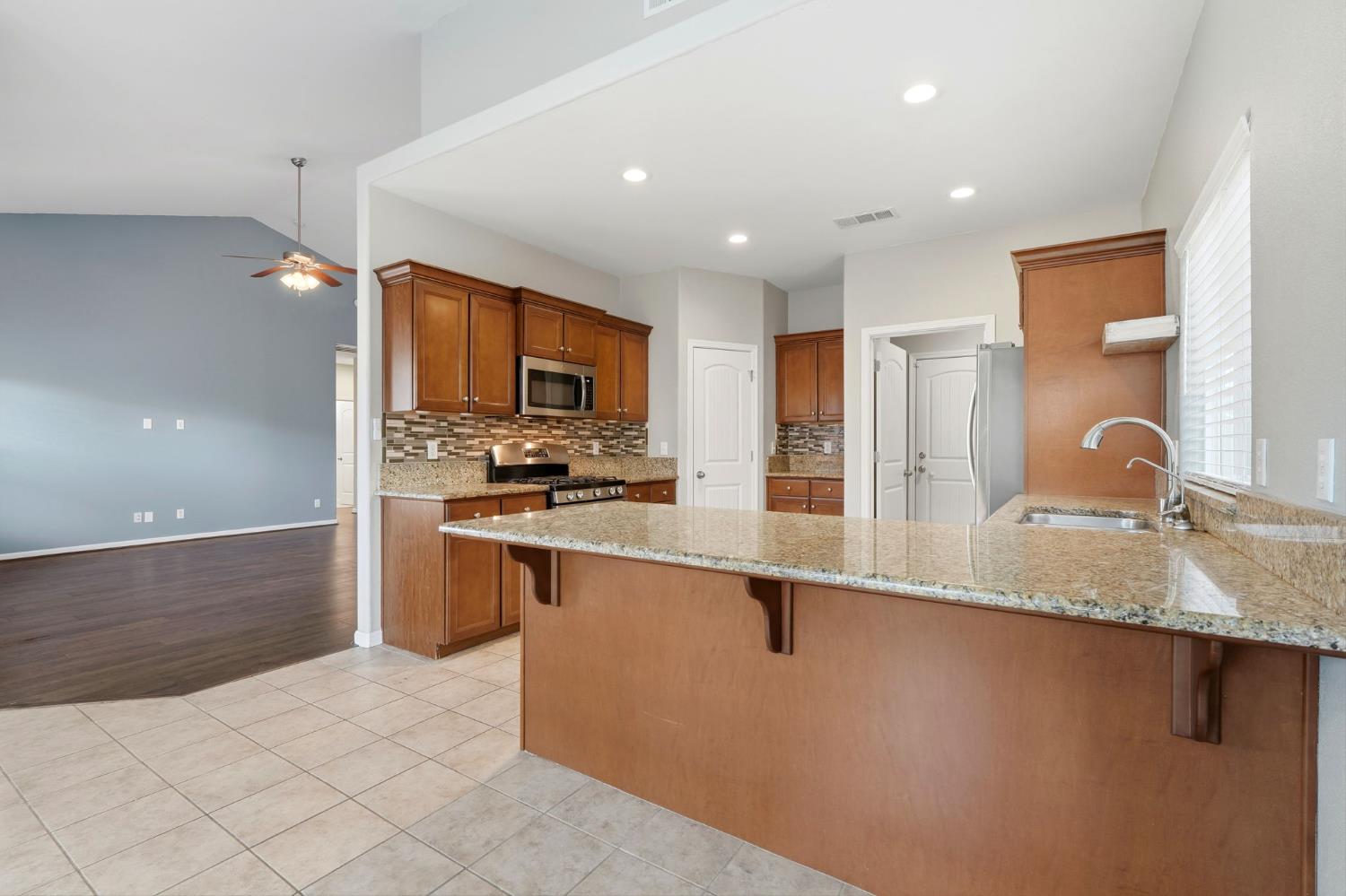 1206 North Kaplan Place Hanford, CA 93230 - Photo 22 of 52 a kitchen with stainless steel appliances granite countertop a sink and a refrigerator