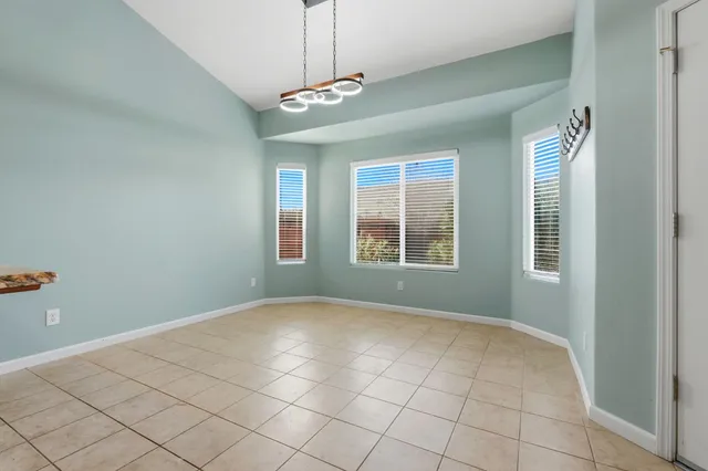 an empty room with wooden floor cabinet and windows