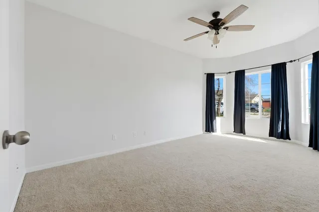 an empty room with a ceiling fan and carpet