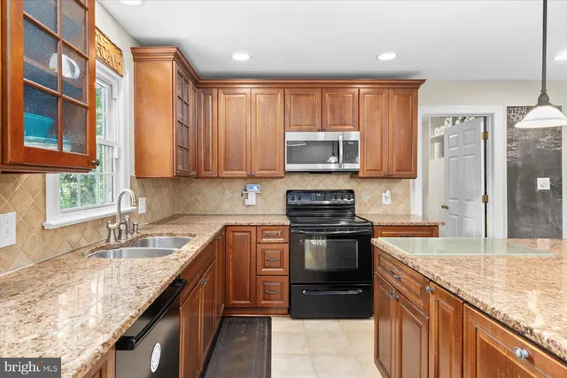 a kitchen with stainless steel appliances granite countertop a stove a sink and a microwave