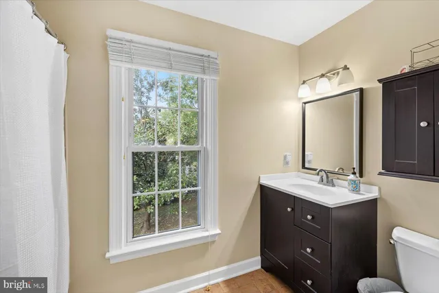 a bathroom with a double vanity sink toilet mirror and window