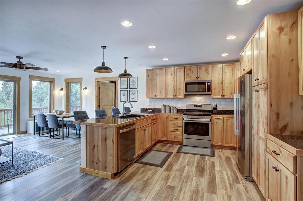1002 Venture Road Fairplay, CO 80440 - Photo 10 of 35 a kitchen with stainless steel appliances granite countertop a stove top oven a sink dishwasher a refrigerator and a dining table with wooden floor