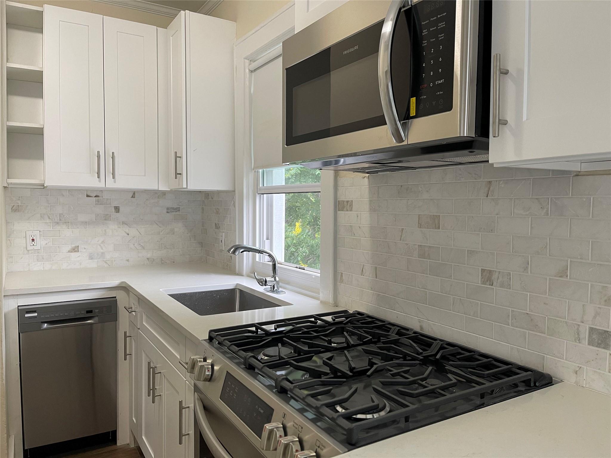 47 North High Street, Unit 2 Tuckahoe, NY 10707 - Photo 1 of 1 Kitchen featuring stainless steel appliances, white cabinetry, decorative backsplash, and light countertops