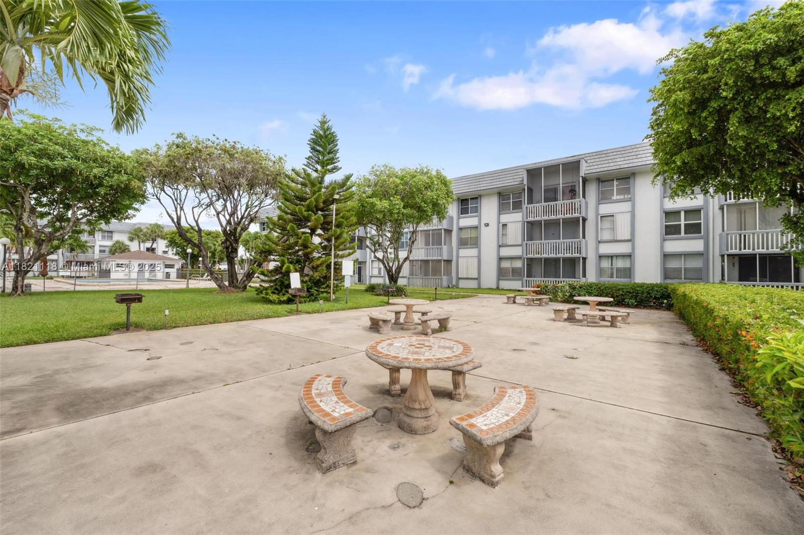 6705 Northwest 169th Street, Unit C310 Hialeah, FL 33015 - Photo 5 of 26 a view of a patio with couches and table and chairs next to yard and trees