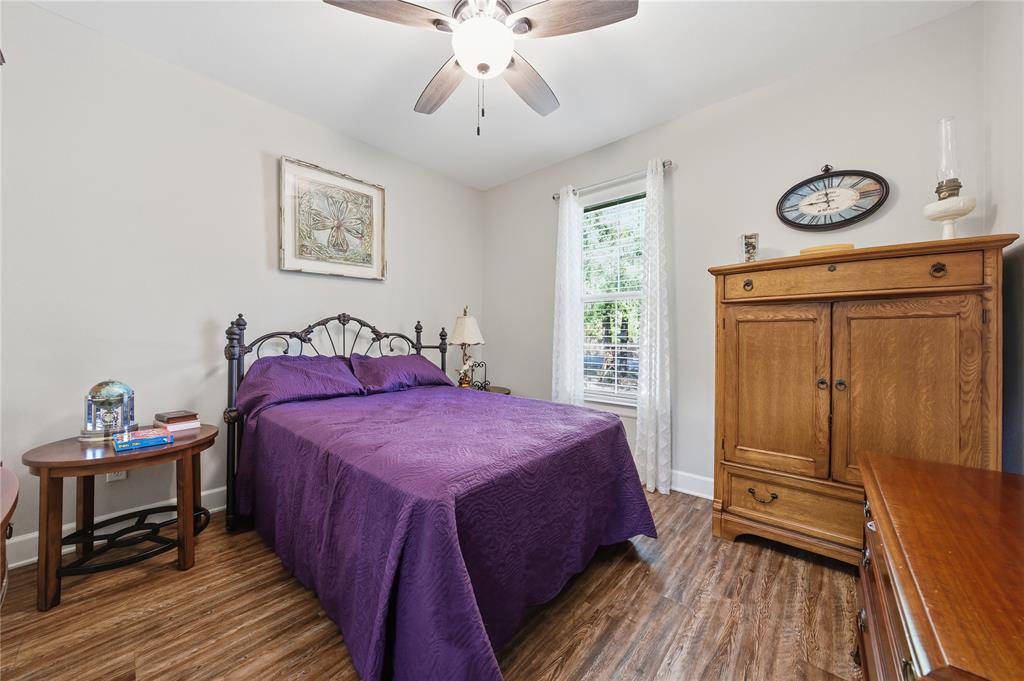 7222 Neches Street Athens, TX 75752 - Photo 12 of 27 a bedroom with a bed and a chandelier