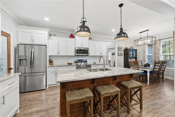 a kitchen with stainless steel appliances granite countertop a center island a stove a dining table and chairs