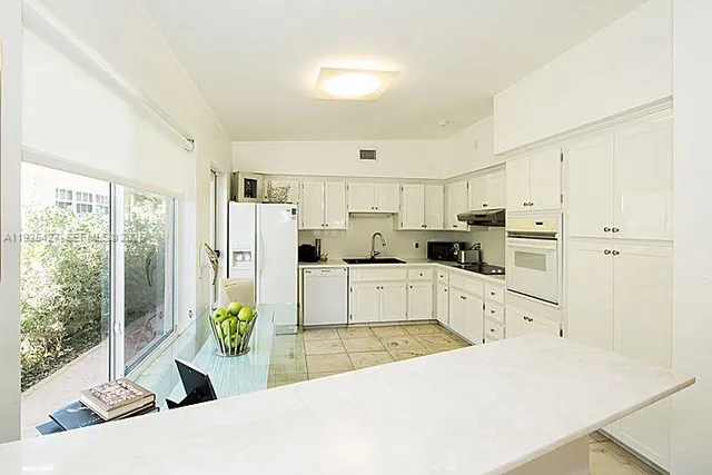 a kitchen with stainless steel appliances kitchen island granite countertop a refrigerator a stove a sink dishwasher and white cabinets with wooden floor