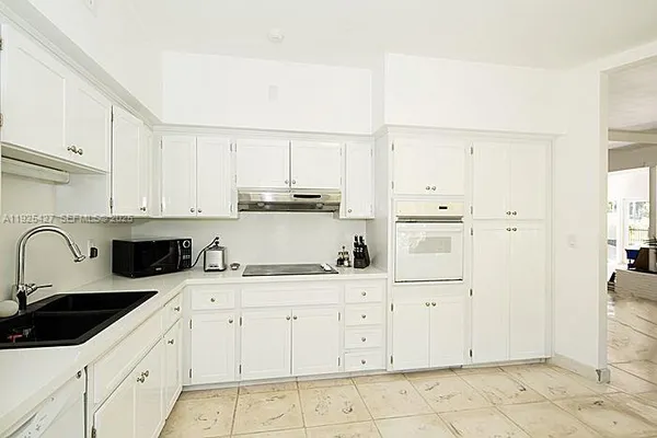 a kitchen with white cabinets a sink and white appliances