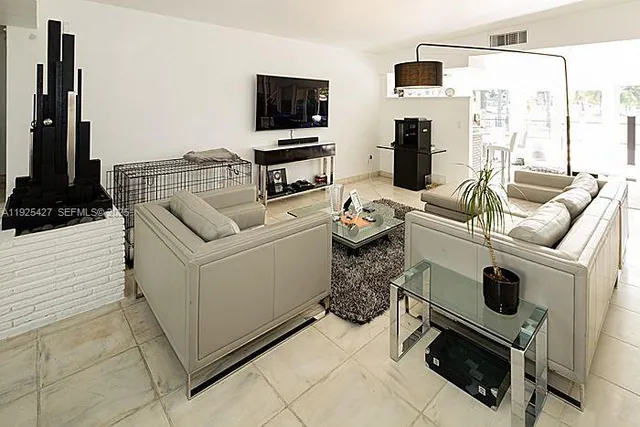 a living room with furniture a flat screen tv and floor to ceiling window