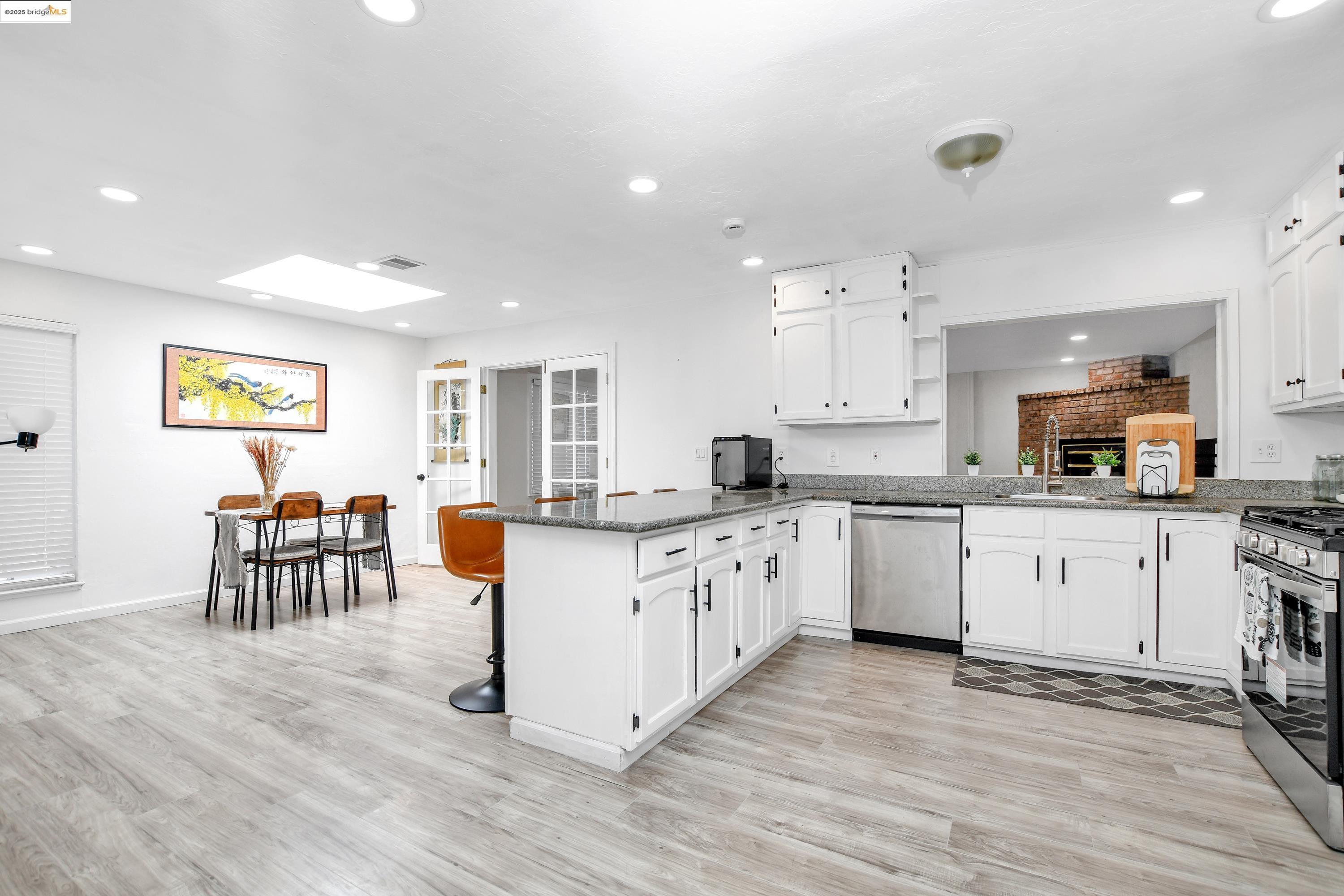 185 Evening Star Court Milpitas, CA 95035 - Photo 21 of 33 a large kitchen with granite countertop a stove top oven a sink a dining table and chairs with wooden floor