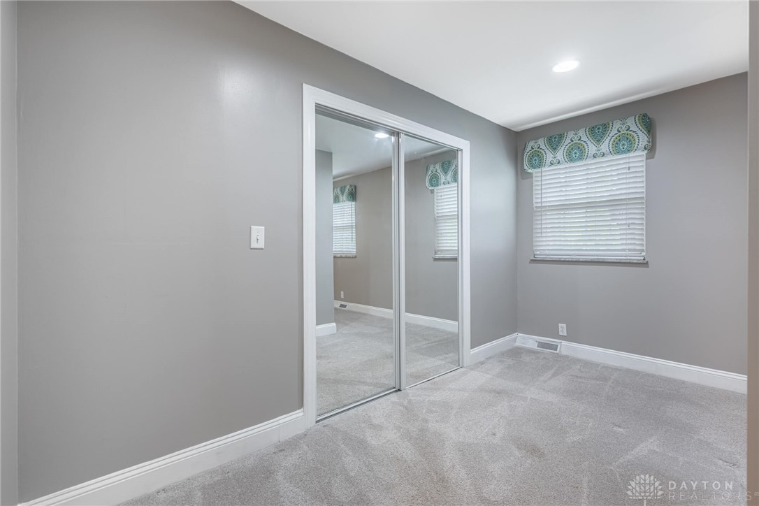 467 West Rahn Road Dayton, OH 45429 - Photo 21 of 41 This cozy bedroom features plush carpet and mirrored closet doors, creating an inviting and bright space.