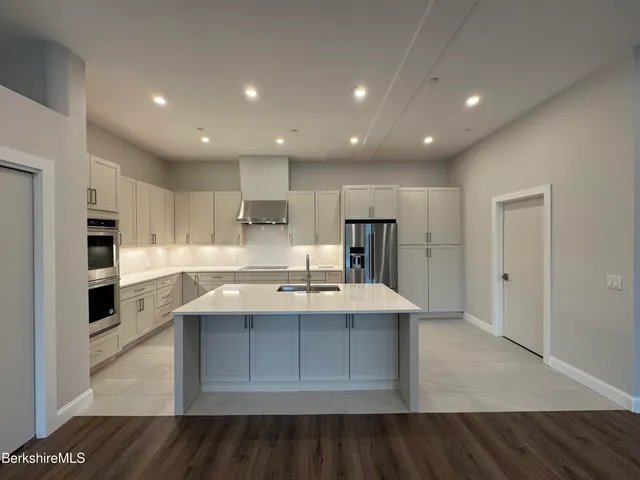 a large kitchen with stainless steel appliances a refrigerator and a stove top oven