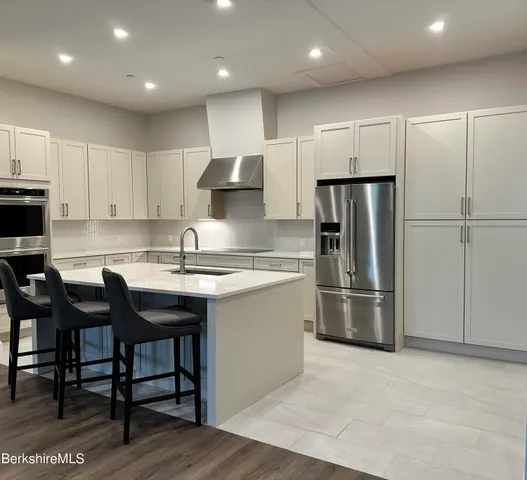 a view of an empty room with kitchen and window