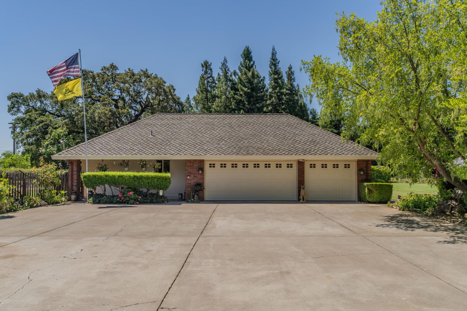 9069 Bader Road Elk Grove, CA 95624 - Photo 10 of 70 Ranch-style residence featuring an attached three-car garage with individual doors, a concrete driveway, and mature landscaping