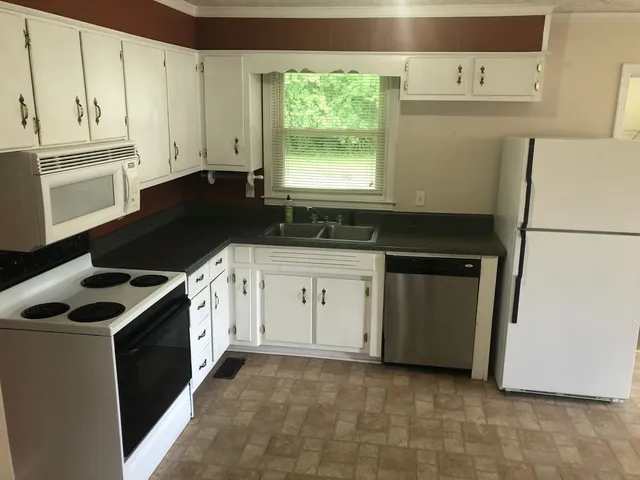 a kitchen with granite countertop white cabinets and white appliances