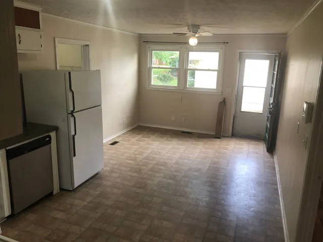 an empty room with windows and refrigerator